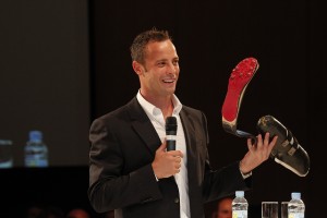 Pistorius global sports forum Pistorius speaking holds up his prothestic running leg to the audience at the Global Sports Forum