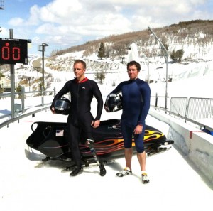 Coach_Holm_and_Cody_photoshoot2 Coach Holm and athlete Cody pose in front of bobsled.
