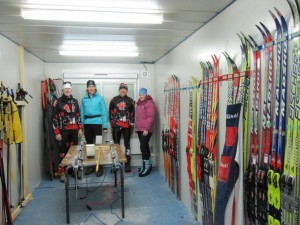 Wax room Four athletes and coaches standing in a wax room surrounded by skis.
